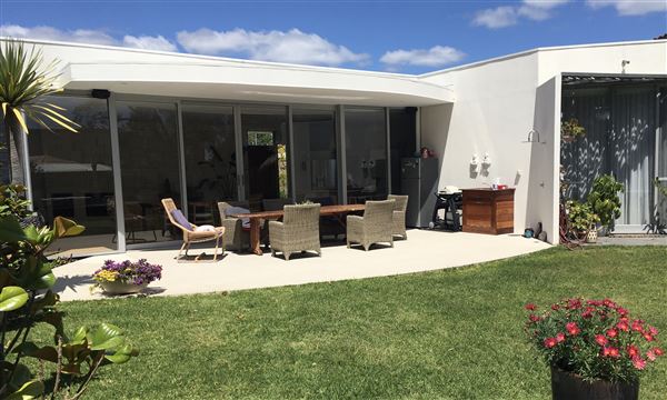 Dunsborough Beach House - Inside the house is a huge open kitchen, living dining, lounge, area with limestone wall and wood fire. The kitchen has triangular island bench. The pictures show the front of house in different seasons. Also included is a view of the street which shows that its super quiet with heaps of parking. We also have 2 different parking areas at the house which could easily accommodate 10 cars. The living open area is super light and has lots of plants and this opens out to the backyard through a wall of glass stacker doors which blends the indoor/outdoor areas. There a large white limestone curved wall in the backyard and the pool. (8/11/2021 - Credits: Michelle Cameron-Brown)