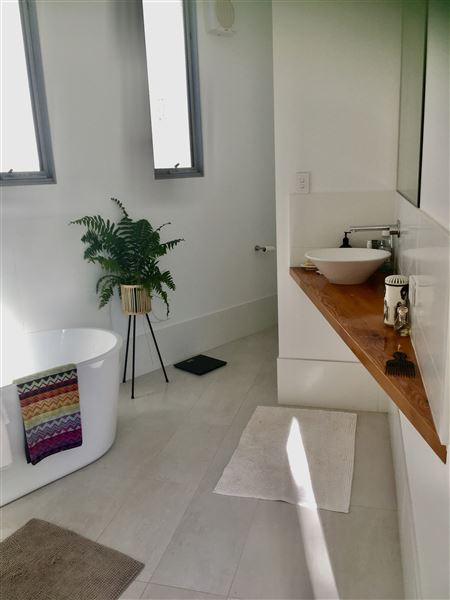 Dunsborough Beach House - Inside the house is a huge open kitchen, living dining, lounge, area with limestone wall and wood fire. The kitchen has triangular island bench. The pictures show the front of house in different seasons. Also included is a view of the street which shows that its super quiet with heaps of parking. We also have 2 different parking areas at the house which could easily accommodate 10 cars. The living open area is super light and has lots of plants and this opens out to the backyard through a wall of glass stacker doors which blends the indoor/outdoor areas. There a large white limestone curved wall in the backyard and the pool. (8/11/2021 - Credits: Michelle Cameron-Brown)
