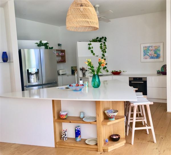 Dunsborough Beach House - Inside the house is a huge open kitchen, living dining, lounge, area with limestone wall and wood fire. The kitchen has triangular island bench. The pictures show the front of house in different seasons. Also included is a view of the street which shows that its super quiet with heaps of parking. We also have 2 different parking areas at the house which could easily accommodate 10 cars. The living open area is super light and has lots of plants and this opens out to the backyard through a wall of glass stacker doors which blends the indoor/outdoor areas. There a large white limestone curved wall in the backyard and the pool. All areas are available for filming. (18/02/2022 - Credits: Michelle Cameron-Brown)