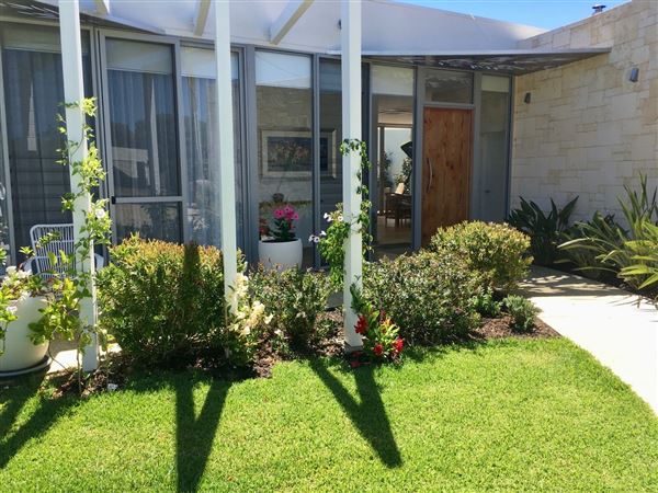 Dunsborough Beach House - Inside the house is a huge open kitchen, living dining, lounge, area with limestone wall and wood fire. The kitchen has triangular island bench. The pictures show the front of house in different seasons. Also included is a view of the street which shows that its super quiet with heaps of parking. We also have 2 different parking areas at the house which could easily accommodate 10 cars. The living open area is super light and has lots of plants and this opens out to the backyard through a wall of glass stacker doors which blends the indoor/outdoor areas. There a large white limestone curved wall in the backyard and the pool. All areas are available for filming. (18/02/2022 - Credits: Michelle Cameron-Brown)